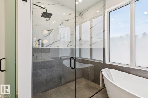Bathroom featuring a glass-enclosed shower with a black rain showerhead, a freestanding bathtub, and large windows - 11146 62 Street Nw, Edmonton, AB - Indoor Photo Showing Bathroom
