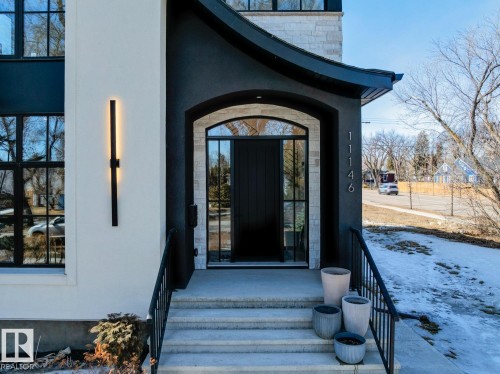 The property features a striking entrance with a black arched front door, complemented by a black metal railing and exterior light fixture - 11146 62 Street Nw, Edmonton, AB - Outdoor