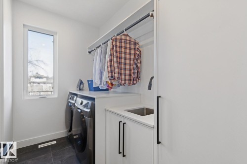 The utility room features a window providing natural light, a laundry sink with a faucet, and a clothes hanging rod - 11146 62 Street Nw, Edmonton, AB - Indoor Photo Showing Laundry Room