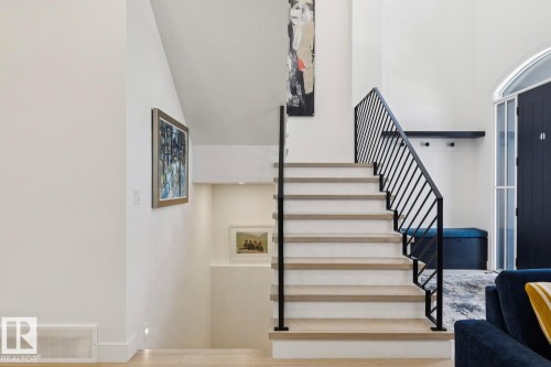 The property features a staircase with light-toned treads and risers, complemented by a contemporary black metal railing - 11146 62 Street Nw, Edmonton, AB - Indoor Photo Showing Other Room