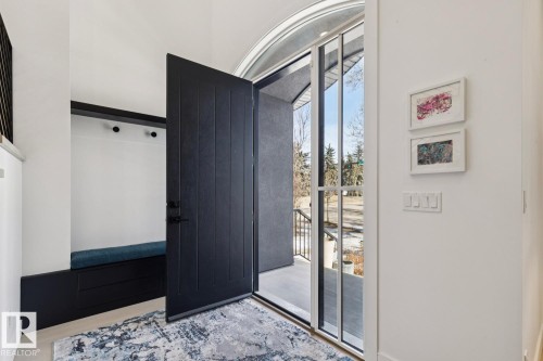 The entryway features a dark paneled door, a built-in bench with a blue cushion, and a rug with a blue and grey abstract pattern - 11146 62 Street Nw, Edmonton, AB -  With Exterior