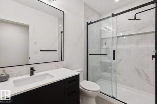 The bathroom features a sleek vanity with a rectangular sink and a matte black faucet, complemented by a large mirror with a black frame - 11146 62 Street Nw, Edmonton, AB - Indoor Photo Showing Bathroom