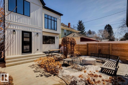 The property features white board and batten siding, black-framed windows, and a black front door with glass panels - 11146 62 Street Nw, Edmonton, AB - Outdoor With Exterior
