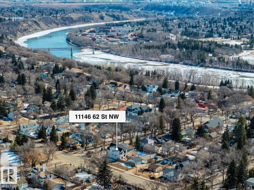 Aerial view showcasing the property within a neighborhood of detached residences, featuring a distant river with a bridge, and surrounding wooded areas - 11146 62 Street Nw, Edmonton, AB - Outdoor With View