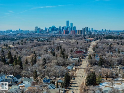 Aerial view of the neighborhood featuring a clear blue sky, distant city skyline, and residential properties with surrounding trees - 11146 62 Street Nw, Edmonton, AB - Outdoor With View