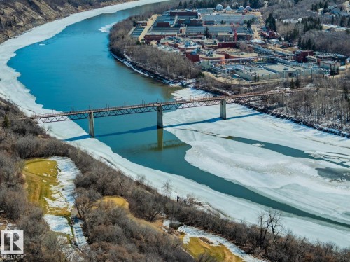 Aerial view featuring a river with partial ice coverage, a bridge with a metal truss structure, and surrounding wooded areas - 11146 62 Street Nw, Edmonton, AB - Outdoor With Body Of Water With View