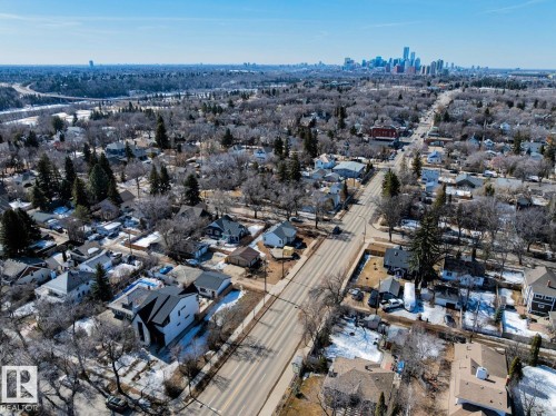 Aerial view of the neighborhood featuring residential properties and tree-lined streets, with a distant city skyline visible under a clear sky - 11146 62 Street Nw, Edmonton, AB - Outdoor With View