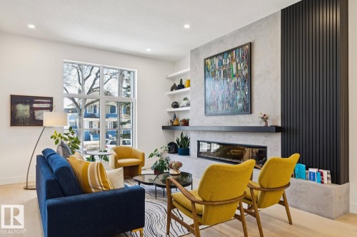 Living space featuring light-toned flooring, a fireplace with a stone surround, and an expansive window providing natural light - 11146 62 Street Nw, Edmonton, AB - Indoor Photo Showing Living Room With Fireplace