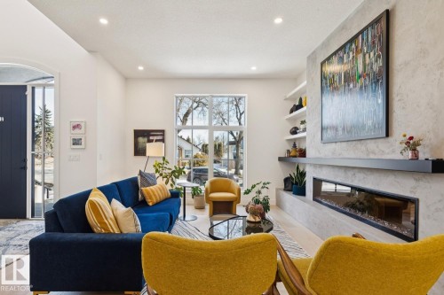 This living area features light hardwood flooring, a modern linear fireplace, and a large window providing natural light - 11146 62 Street Nw, Edmonton, AB - Indoor Photo Showing Living Room With Fireplace