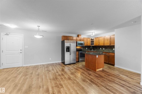 This property features an open-concept living space with wood-look flooring throughout - 319 17415 99 Avenue, Edmonton, AB - Indoor Photo Showing Kitchen
