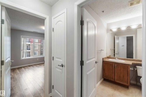The property features a bathroom with a wooden vanity, a sink, a mirror, and overhead lighting - 319 17415 99 Avenue, Edmonton, AB - Indoor