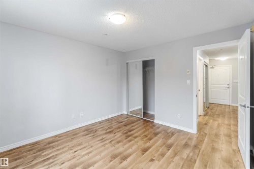 This room features light-toned wood flooring and a mirrored closet - 319 17415 99 Avenue, Edmonton, AB - Indoor Photo Showing Other Room