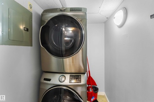 The property includes a dedicated laundry area with a stacked washer and dryer unit, a wall-mounted electrical panel, and an overhead light fixture - 319 17415 99 Avenue, Edmonton, AB - Indoor Photo Showing Laundry Room
