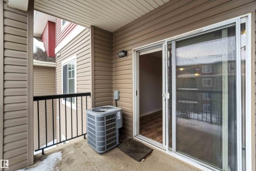 This balcony features a concrete floor, a black metal railing, and a sliding glass door providing direct access to the interior - 319 17415 99 Avenue, Edmonton, AB - Outdoor With Exterior