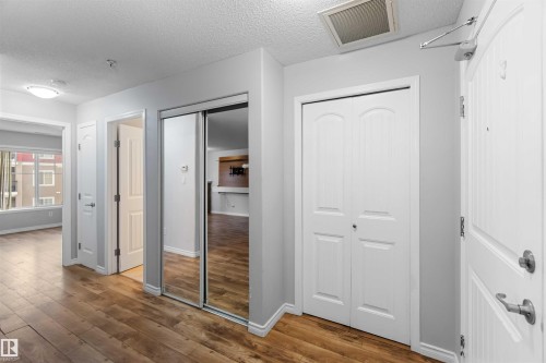 Entryway featuring hardwood-style flooring, a mirrored closet, and a white bi-fold closet - 319 17415 99 Avenue, Edmonton, AB - Indoor Photo Showing Other Room
