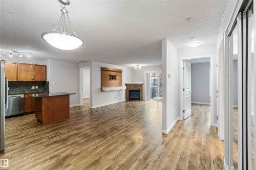 This property features an open-concept living space with wood-look flooring throughout - 319 17415 99 Avenue, Edmonton, AB - Indoor With Fireplace