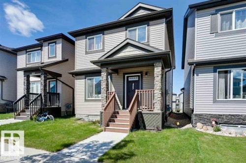 The property features a two-story exterior with light-colored siding, a covered front porch with stone pillars, and wooden steps leading to the entrance - 1536 21 Street, Edmonton, AB - Outdoor With Facade