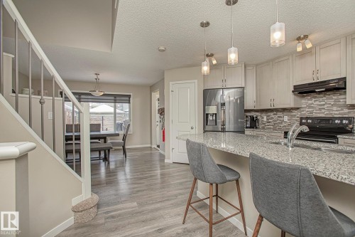 This property features an open-concept kitchen with a large island, granite countertops, and light-colored cabinetry - 7718 Eifert Crescent, Edmonton, AB - Indoor Photo Showing Kitchen With Upgraded Kitchen