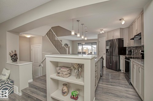 Kitchen with light-colored cabinetry, a dark-colored refrigerator, and a dark tile backsplash - 7718 Eifert Crescent, Edmonton, AB - Indoor Photo Showing Kitchen With Upgraded Kitchen