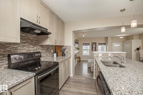 The kitchen features light-toned cabinetry, granite countertops, and a mosaic tile backsplash - 7718 Eifert Crescent, Edmonton, AB - Indoor Photo Showing Kitchen With Double Sink With Upgraded Kitchen