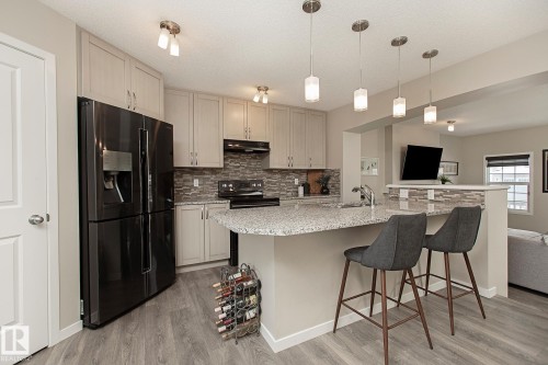 Modern kitchen featuring light-colored cabinetry, a black French door refrigerator, and a speckled gray countertop with an integrated sink - 7718 Eifert Crescent, Edmonton, AB - Indoor Photo Showing Kitchen With Upgraded Kitchen