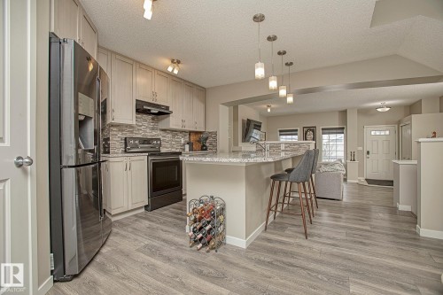 Well-appointed kitchen featuring stainless steel appliances, light-toned cabinetry, and a textured tile backsplash - 7718 Eifert Crescent, Edmonton, AB - Indoor Photo Showing Kitchen With Upgraded Kitchen
