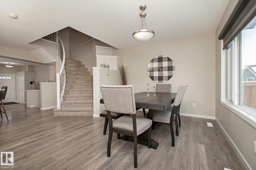 This property features a dining area with a modern light fixture, a large window, and light-toned walls - 7718 Eifert Crescent, Edmonton, AB - Indoor Photo Showing Dining Room