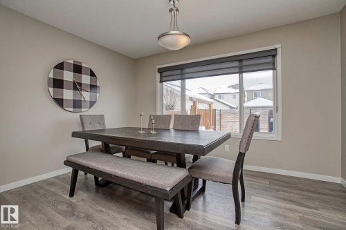 Dining area featuring light-colored walls, a large window with shades, and wood-style flooring - 7718 Eifert Crescent, Edmonton, AB - Indoor Photo Showing Dining Room