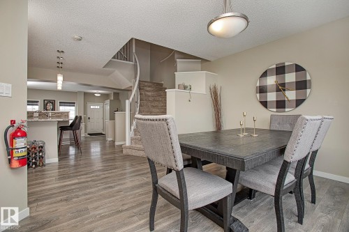 The dining area features hard surface flooring and a contemporary light fixture - 7718 Eifert Crescent, Edmonton, AB - Indoor Photo Showing Dining Room