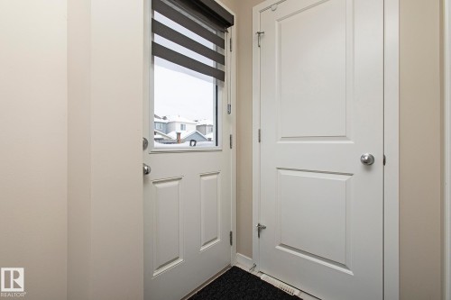 Entryway with a white paneled door featuring a window with blinds, and an additional white paneled door - 7718 Eifert Crescent, Edmonton, AB - Indoor Photo Showing Other Room