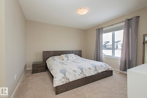 The bedroom features neutral-toned walls, carpeted flooring, and a window with curtains - 7718 Eifert Crescent, Edmonton, AB - Indoor Photo Showing Bedroom