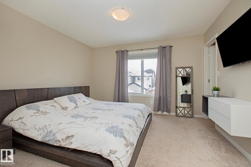 This room features neutral-toned walls and carpeting, a window with curtains, and a ceiling light fixture - 7718 Eifert Crescent, Edmonton, AB - Indoor Photo Showing Bedroom