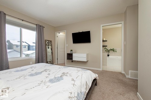 This spacious bedroom features neutral wall tones, a large window, and soft carpet flooring - 7718 Eifert Crescent, Edmonton, AB - Indoor Photo Showing Bedroom