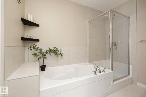 Bathroom featuring a white bathtub with chrome fixtures and a glass-enclosed shower with a rainfall showerhead - 7718 Eifert Crescent, Edmonton, AB - Indoor Photo Showing Bathroom
