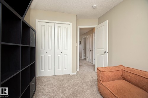 This area of the property features neutral-toned walls, light-colored carpet flooring, and white bifold closet doors - 7718 Eifert Crescent, Edmonton, AB - Indoor