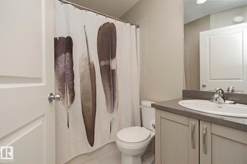 Bathroom featuring a vanity with a countertop and under-sink cabinetry, a toilet, and a shower area with a curtain - 7718 Eifert Crescent, Edmonton, AB - Indoor Photo Showing Bathroom