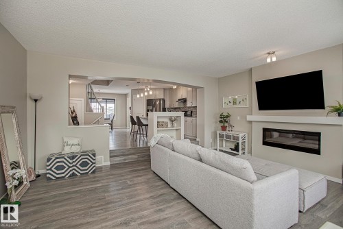 Living area featuring light grey walls, recessed lighting, and grey wood-look flooring - 7718 Eifert Crescent, Edmonton, AB - Indoor Photo Showing Living Room With Fireplace