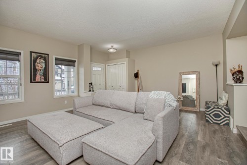 The main living area features durable flooring, ample natural light from two windows with blinds, and neutral-toned walls - 7718 Eifert Crescent, Edmonton, AB - Indoor Photo Showing Living Room