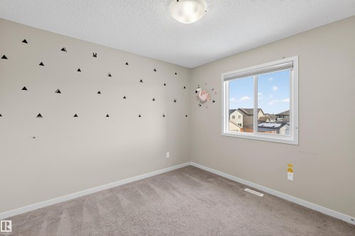 This room features neutral-toned walls, a carpeted floor, and a window providing natural light and views of the surrounding neighborhood - 4723 Alwood Bend, Edmonton, AB - Indoor Photo Showing Other Room