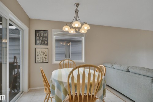 The dining area features a six-light chandelier, a window providing natural light, and tile flooring - 5 Parkview Crescent, Calmar, AB - Indoor Photo Showing Dining Room