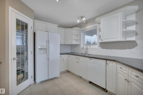 Kitchen featuring white cabinetry, dark countertops, a window over the sink, and tile flooring - 5 Parkview Crescent, Calmar, AB - Indoor Photo Showing Kitchen