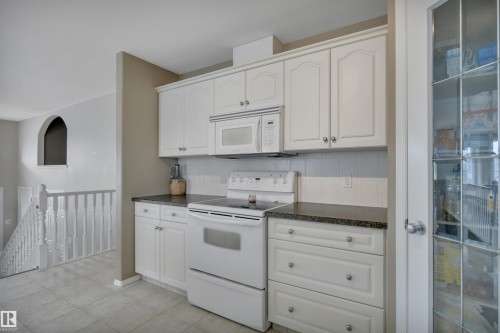 Kitchen featuring white cabinetry, dark countertops, a white electric range, and a white microwave - 5 Parkview Crescent, Calmar, AB - Indoor Photo Showing Kitchen