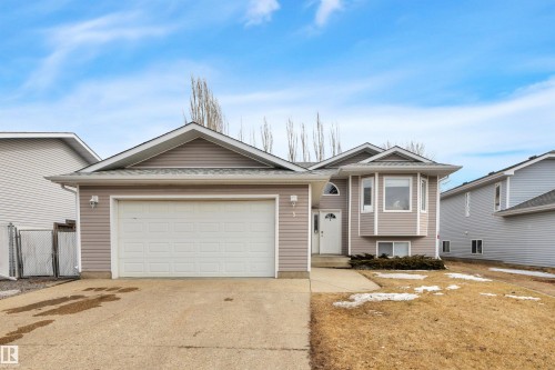 The property features a two-car garage, a light-colored exterior with bay windows, and a concrete driveway - 5 Parkview Crescent, Calmar, AB - Outdoor With Facade