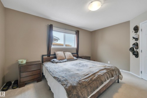 The room features a window with dark curtains, light-colored carpeting, and a ceiling-mounted light fixture - 5 Parkview Crescent, Calmar, AB - Indoor Photo Showing Bedroom