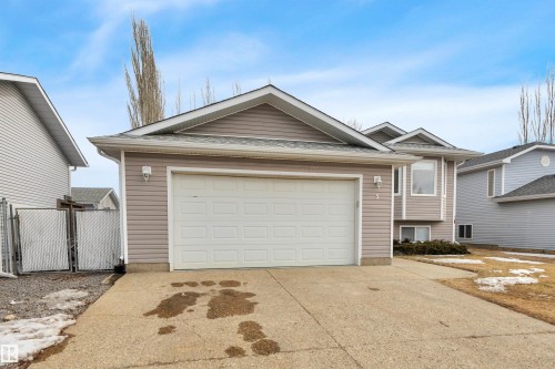 The property features a two-car garage with a panel door, light-colored siding, and a concrete driveway - 5 Parkview Crescent, Calmar, AB - Outdoor