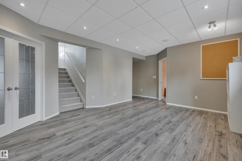 This spacious room features gray wood-style flooring, light gray painted walls, and a white drop ceiling with recessed lighting - 5 Parkview Crescent, Calmar, AB - Indoor Photo Showing Other Room