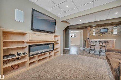 The property features a media wall with built-in shelving and an electric fireplace, set against a backdrop of neutral-toned walls - 5 Parkview Crescent, Calmar, AB - Indoor