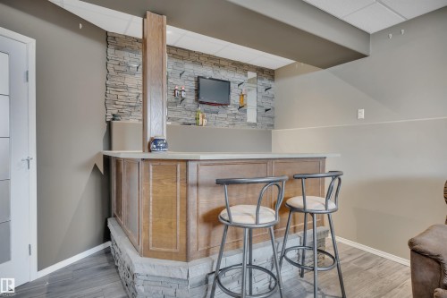 The property features an entertainment space with a wooden bar, a stone accent wall, and recessed lighting - 5 Parkview Crescent, Calmar, AB - Indoor Photo Showing Other Room