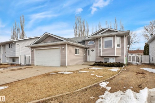 The property features light gray siding, a white garage door, and a white front door with an arched window above - 5 Parkview Crescent, Calmar, AB - Outdoor With Facade