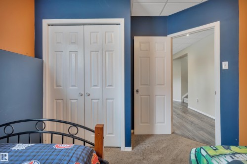 This room features a neutral carpet, white trim, and a combination of blue and orange painted walls - 5 Parkview Crescent, Calmar, AB - Indoor Photo Showing Bedroom